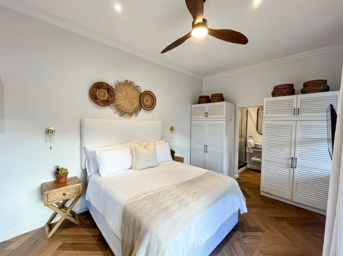 Ibis Cottage bedroom with louvred wardrobes and an ensuite glimpse